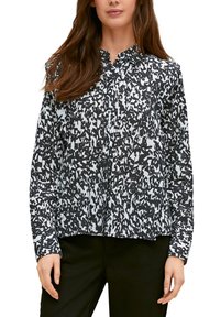 Zwart-wit geblokte blouse met lange mouwen en een kraag, gekenmerkt door een mix van abstracte vormen en een losse pasvorm. Gladde stoftextuur.