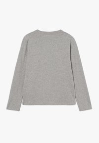 Dlouhý rukáv, tričko s kulatým výstřihem ve světle šedé bavlně, které se vyznačuje hladkou texturou a bočními rozparky na lemu pro snadný pohyb.