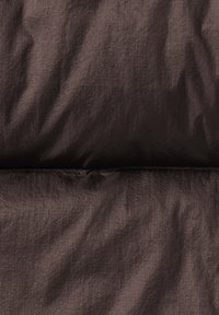 Tessuto puffo marrone scuro con una consistenza liscia, caratterizzato da pieghe e una leggera lucentezza. La superficie appare leggera e resistente all'acqua.