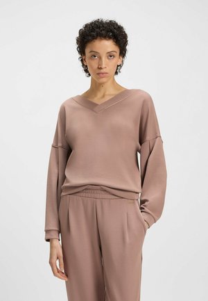 Maglietta rosa polveroso a maniche lunghe con scollatura a V e spalle cadute, realizzata in tessuto morbido, abbinata a pantaloni a sigaretta coordinati con vita elastica.