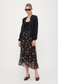 Black bomber jacket with silver zipper, black tank top, floral-patterned midi skirt with ruffled hem, and maroon shoes.
