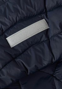 Tejido acolchado de puffer en color navy con una textura suave. Presenta una etiqueta texturizada plateada con la inscripción "name it" en relieve. Detalles de costura visibles.
