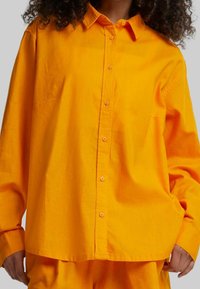 Ljust gul överdimensionerad skjorta med klassisk krage, knappstängning framtill och långa ärmar. Tillverkad av mjukt, lättviktigt tyg.