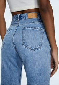 Světle modré džíny s vysokým pasem z denimu, s dvěma zadními kapsami, koženou značkovou nášivkou a mírně vybledlou texturou.