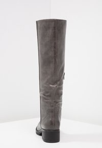 Botte haute jusqu'au genou en cuir gris avec une texture lisse, une forme droite et un petit talon bloc. Elle présente un détail de couture et une fermeture éclair latérale.