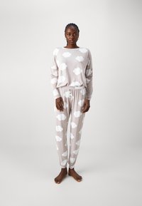 Ljusbeige pyjamas set med vita molnmönster, inklusive en långärmad topp och byxor med elastisk midja. Mjukt tyg och avslappnad passform.