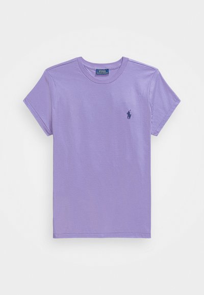 Īsām piedurknēm, apaļa kakla T-kreklu no mīksta lavandas krāsas kokvilnas. Uz krūtīm ir neliels tumši zils logo. Gluda tekstūra ar standarta piegriezumu.