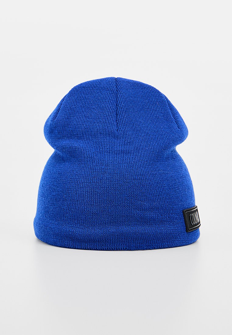 Bonnet tricoté bleu avec une texture douce, présentant un ourlet replié et une étiquette en tissu noir sur le côté. Design à sommet arrondi.