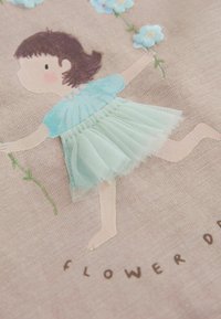 Katoenen stof met een cartoonmeisje in een blauw shirt en een mintkleurige tule rok, met geborduurde bloemen en de tekst "FLOWER DANCING" eronder.