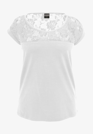 Blusa blanca de manga corta con patrón floral de encaje en el pecho y los hombros, tela lisa debajo.