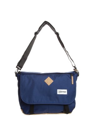 Sac messager Eastpak bleu avec bandoulière réglable noire, rabat avant, accents marron clair et patch logo sur le panneau frontal central.
