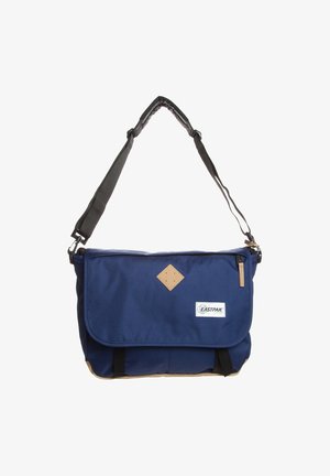 Blue Eastpak messenger bag with black adjustable shoulder strap, front flap, tan accents, and logo patch on center front panel.