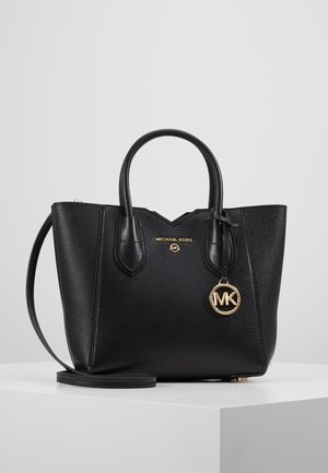 Zwarte textuurleren Michael Kors handtas met dubbele handvatten, gouden logohanger en afneembare schouderriem op een witte ondergrond.