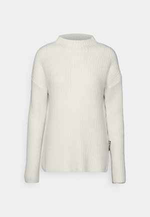 Hvid ribstrikket sweater med lange ærmer og rund halsudskæring, med en lille sort stofmærke på den nederste side.