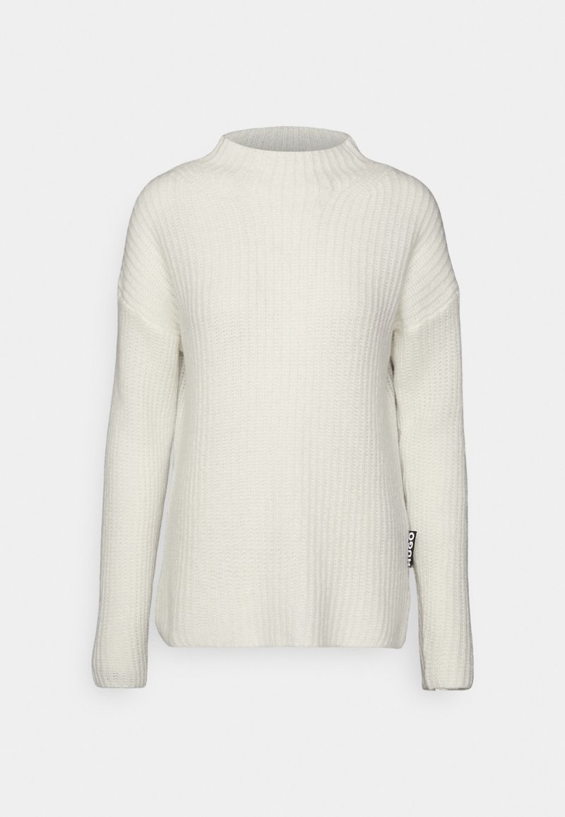 Pull en tricot côtelé blanc à manches longues et col rond, avec une petite étiquette en tissu noire sur le côté inférieur.