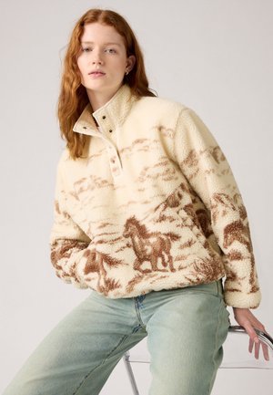 Cremfarbener Fleece-Pullover mit hohem Kragen, der mit einem braunen Pferdemuster versehen ist. Er verfügt über Druckknöpfe und eine weiche, strukturierte Oberfläche.