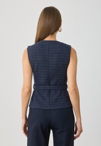 Top fără mâneci, de culoare bleumarin, cu un design texturat, cu talie ajustată și o curea. Materialul prezintă un model în carouri orizontale și marginile desfăcute.