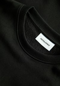 Черна блуза с кръгло деколте с рипсено яка и бял етикет с марката Jack & Jones.