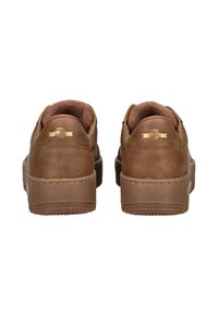 Un paio di sneakers basse in pelle marrone viste da dietro, con colletto imbottito e emblema dorato sulla linguetta del tallone.