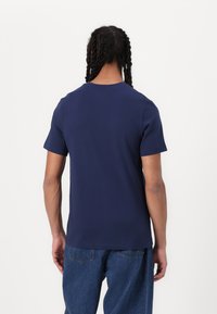 Mørkeblå bomulds T-shirt med korte ærmer, klassisk rund halsudskæring og løs pasform. Bagsiden viser en glat tekstur og en enkel design.