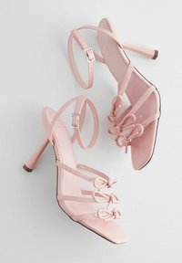 Rosa High-Heels Sandalen mit mehreren dünnen Riemen, dekorativen Schlaufenakzenten und einer quadratischen Schnalle. Glattes, glänzendes Material mit einer spitzen Zehe.