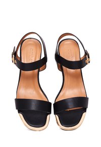 Zwarte leren sandalen met een blokhak en een enkelbandje. Heeft een gouden accent op de teen en een gladde tan voering.