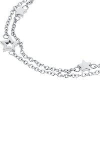 Zilveren dubbele kettingarmband met stervormige bedels, inclusief één holle ster, weergegeven op een witte achtergrond.