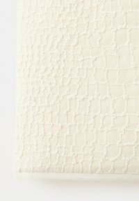 Tissu de couleur crème avec un motif quadrillé en relief texturé et des détails tissés subtils.
