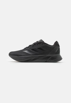 Pantofi sport negri cu un superior din plasă, design cu șireturi, siluetă elegantă și talpă din cauciuc texturată cu dungi subtile de accent.