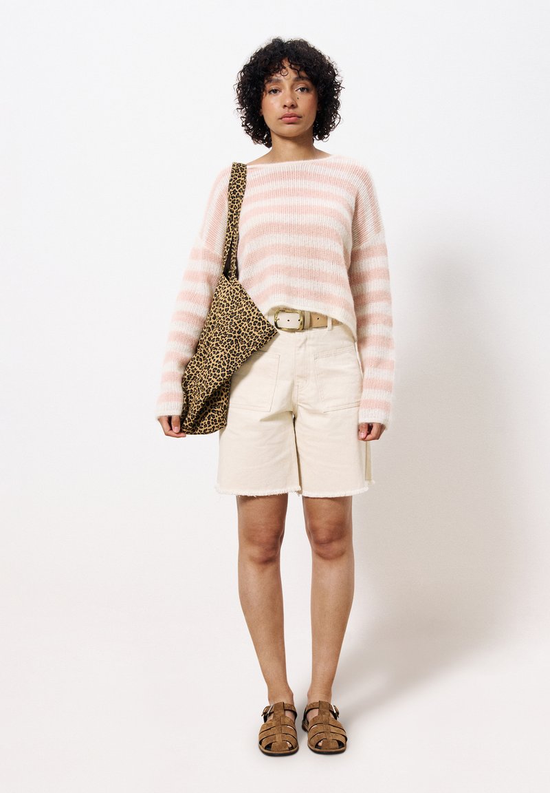 Gestreifter rosa-weißer Strickpullover, beiger Shorts mit fransigen Kanten, Umhängetasche im Leopardenmuster und braune Sandalen mit Riemendetails.