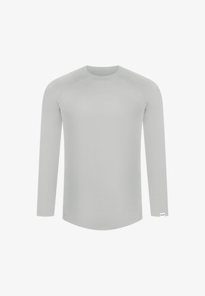 Langærmet skjorte i lys grå, lavet af glat stof. Har rund halsudskæring og afrundet kant med subtile syning detaljer.