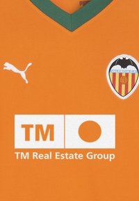 Oranžinė futbolo marškinė su žaliu V formos apykakle, baltu Puma logotipu, Valencia CF herbu ir baltu TM Real Estate Group logotipu centre.