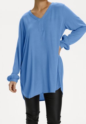 Lys blå langærmet top med V-hals og elastiske manchetter. Stoffet har en glat tekstur, med en afslappet pasform og længere bagkant.