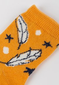 Orange gestrickte Socke mit weißen Federn, Marineblauen Sternen und weißen Punkten. Weicher Stoff und mit einem gerippten Bündchen für angenehmes Tragen.