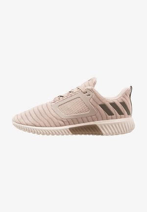 Baskets de sport en mesh beige clair avec semelle texturée, trois bandes foncées au talon et une languette à l'arrière.