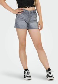 Denimshorts i ljusgrått med standardmidja och uppvikta fållar, kombinerade med svarta höga sneakers med vita snören.