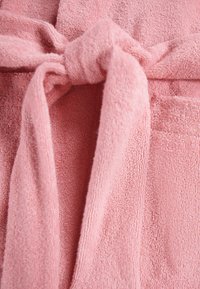 Accappatoio rosa realizzato in un morbido tessuto a trama, con cintura in vita annodata e un design semplice senza motivi o decorazioni.