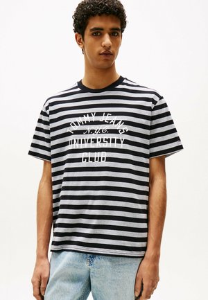 Camiseta a rayas en gris y negro, con el texto blanco "TOMMY JEANS N.Y.C. UNIVERSITY CLUB". Mangas cortas, cuello redondo, ajuste casual.