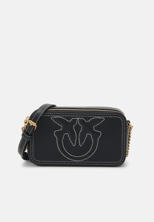 Schwarze Leder-Umhängetasche mit strukturiertem Oberflächen, goldenen Beschlägen, weißen Nähten und einem auffälligen gestickten Logodesign auf der Vorderseite.