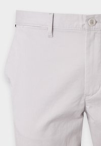 Pantalonii din bumbac gri deschis au un sistem de închidere cu nasture, bretele și buzunare laterale. Materialul are un finisaj neted, cu o ușoară textură.