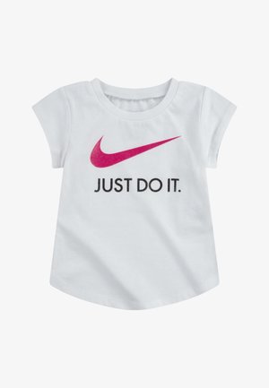 T-shirt de algodão branco com mangas curtas. Apresenta um swoosh rosa da Nike e texto preto "JUST DO IT" no centro. Design de bainha curved.