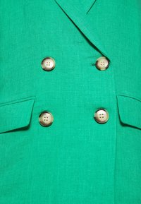 Zelená dvouřadá blazer s kultivovanými zlatými knoflíky, hladkou lněnou texturou a přesně střiženým designem s kapsou.