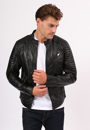 Black leather jacket with quilted shoulder detailing and a zippered chest pocket; features a slim fit and smooth texture.