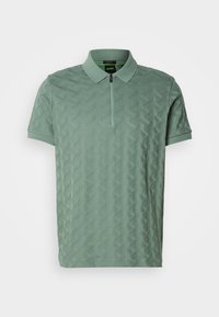 Polo à manches courtes vert clair avec un motif géométrique texturé, patte de boutonnage zippée à l'avant et logo BOSS discret sur le côté gauche de la poitrine.