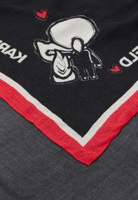 Eșarfă neagră cu accente albe și roșii, având ilustrații cu figuri și inimi. Margini rotunjite cu un bord roșu. Textură textilă moale.