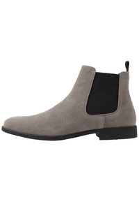 Botas Chelsea em camurça cinza com painéis laterais elásticos, uma alça de puxar e uma sola de borracha preta, caracterizadas por um design elegante e de altura até o tornozelo.