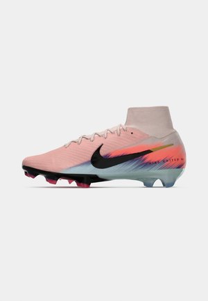 Botas de fútbol Nike en rosa claro con acentos en naranja y azul, con un collar tipo calcetín y logotipo negro, y tacos de goma para tracción.
