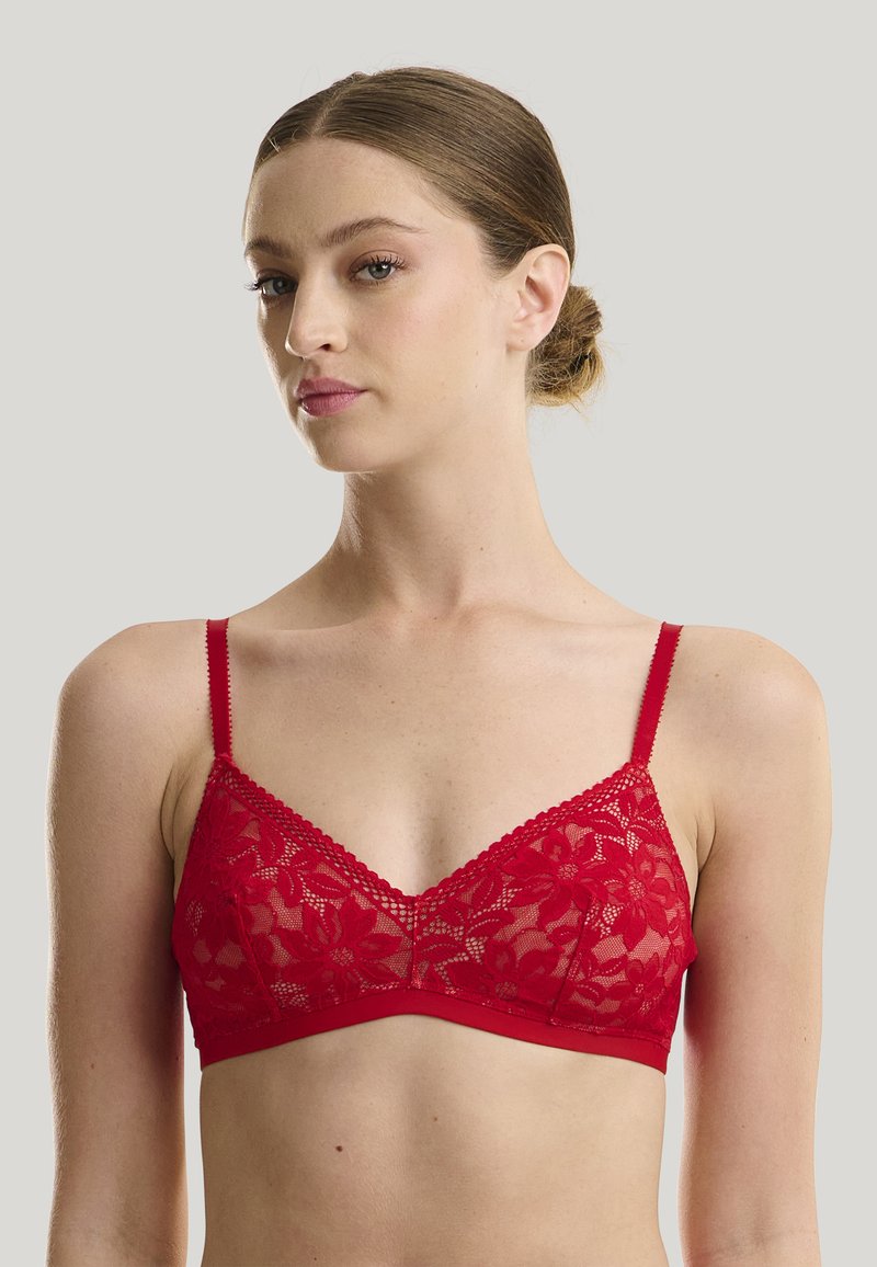 Bralette in pizzo rosso con coppe triangolari, spalline regolabili e design floreale. Presenta un bordo ondulato lungo il décolleté. Tessuto elasticizzato.