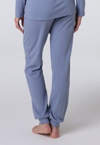 Pantaloni da pigiama a coste di un azzurro chiaro con polsini aderenti. Texture morbida e vestibilità rilassata, dotati di una fascia in vita e di una finitura liscia.