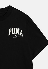 Černé bavlněné tričko s kulatým výstřihem a krátkým rukávem, s bílým vyšívaným logem "PUMA SPORTS" na hrudi.